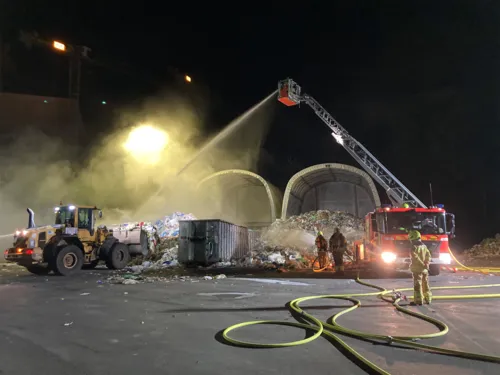 Müll brennt und die Feuerwehr löscht.